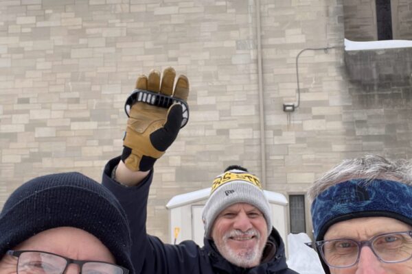 Three men smiling. One waving.