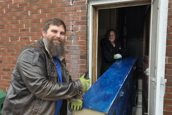 man and woman moving furniture through door