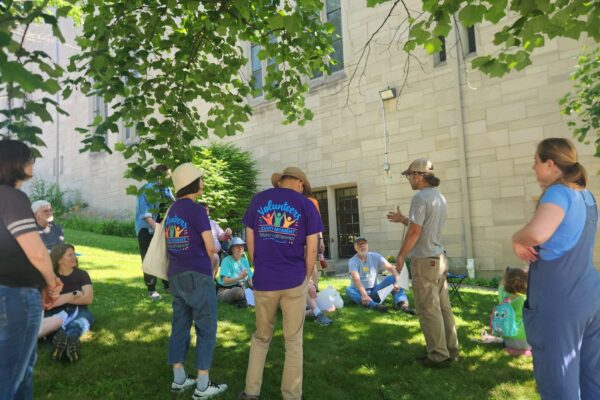 Group of people standing and sitting on the lawn.